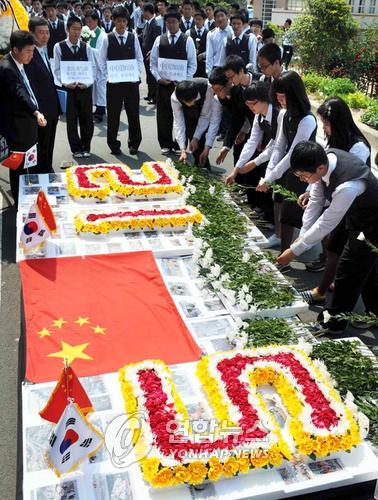 중국 지진 희생자 추모 헌화 (부산=연합뉴스) 조정호 기자 = 21일 부산 사하구 괴정동 동아공고에서 마련한 중국지진 희생자를 위한 헌화식에서 전교생 1천50명이 중국 오성기와 참사현장 사진으로 덮힌 추모단상에 국화꽃을 헌화하고 있다. 이 학교에선 헌화식과 함께 성금모금에 들어갔다. ccho@yna.co.kr