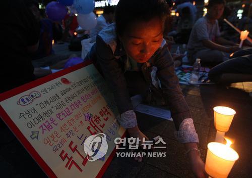 (서울=연합뉴스) 박지호 기자 = 지난 14일 일본 정부가 중등교과서 해설서에 독도 영유권을 명기해 큰 파장이 일고 있는 가운데 15일 오후 서울 청계광장에서 열린 미국산 쇠고기 수입반대 촛불시위 도중 한 시민이 독도 관련 피켓 앞에 촛불을 놓고 있다. jihopark@yna.co.kr 연합뉴스